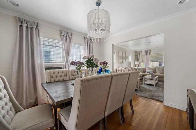 dining area with wood-type flooring, crown molding, baseboards, and a notable chandelier