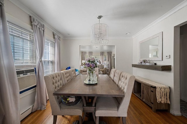 dining area with an inviting chandelier, ornamental molding, wood finished floors, and a baseboard heating unit