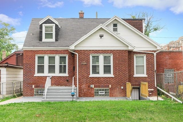 view of front of property featuring a front yard, fence, and brick siding