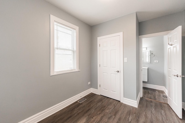 unfurnished bedroom with visible vents, baseboards, and dark wood finished floors