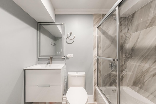 bathroom featuring combined bath / shower with glass door, vanity, and toilet