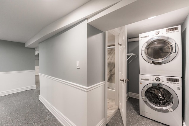 laundry room with laundry area, stacked washer and clothes dryer, and baseboards