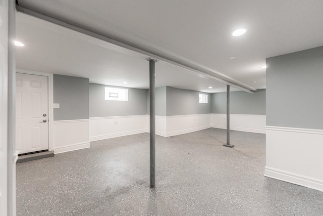 basement with recessed lighting and a wainscoted wall