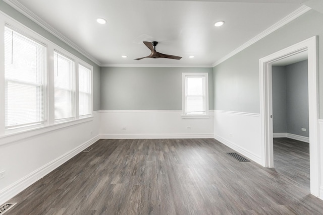 empty room featuring dark wood-style floors, a healthy amount of sunlight, visible vents, and crown molding