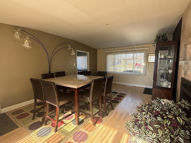 dining space with vaulted ceiling, wood finished floors, and baseboards