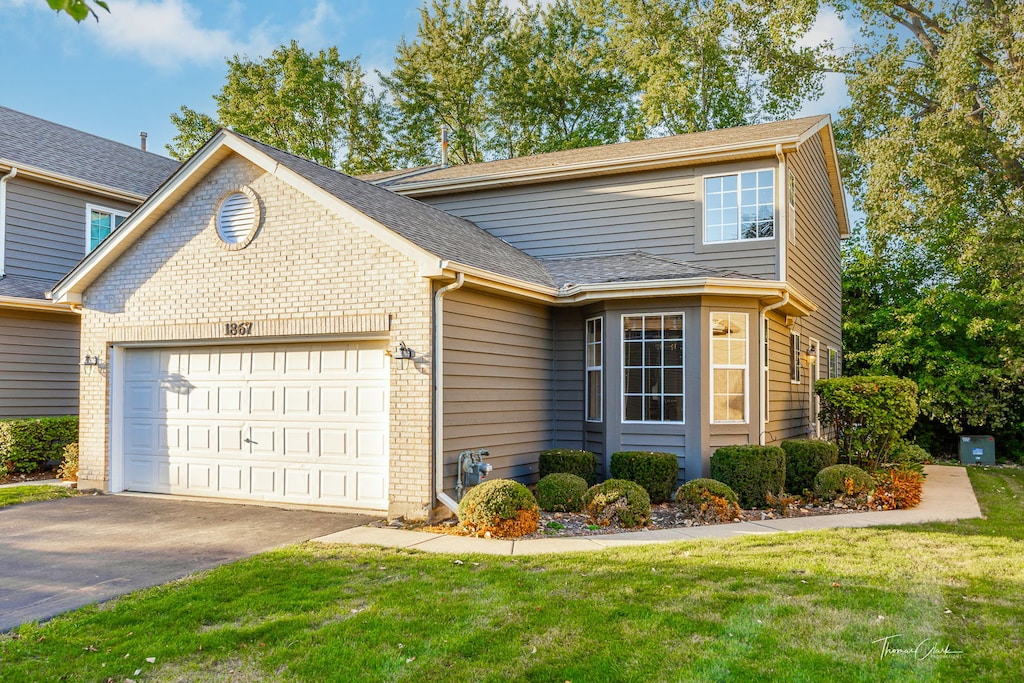 traditional-style home with brick siding, an attached garage, and a front yard