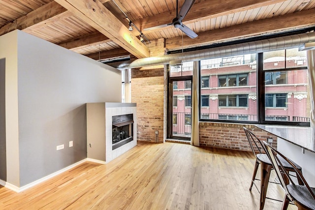 unfurnished living room featuring rail lighting, wood ceiling, a tiled fireplace, and wood finished floors