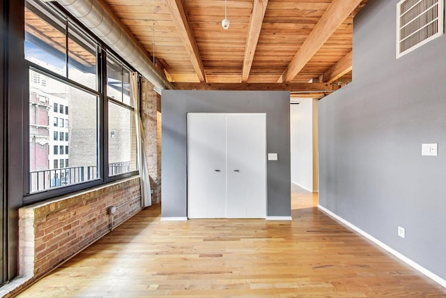 unfurnished room with brick wall, wood ceiling, visible vents, and beamed ceiling