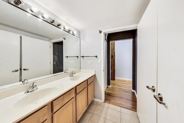 full bath with baseboards, double vanity, a sink, and tile patterned floors