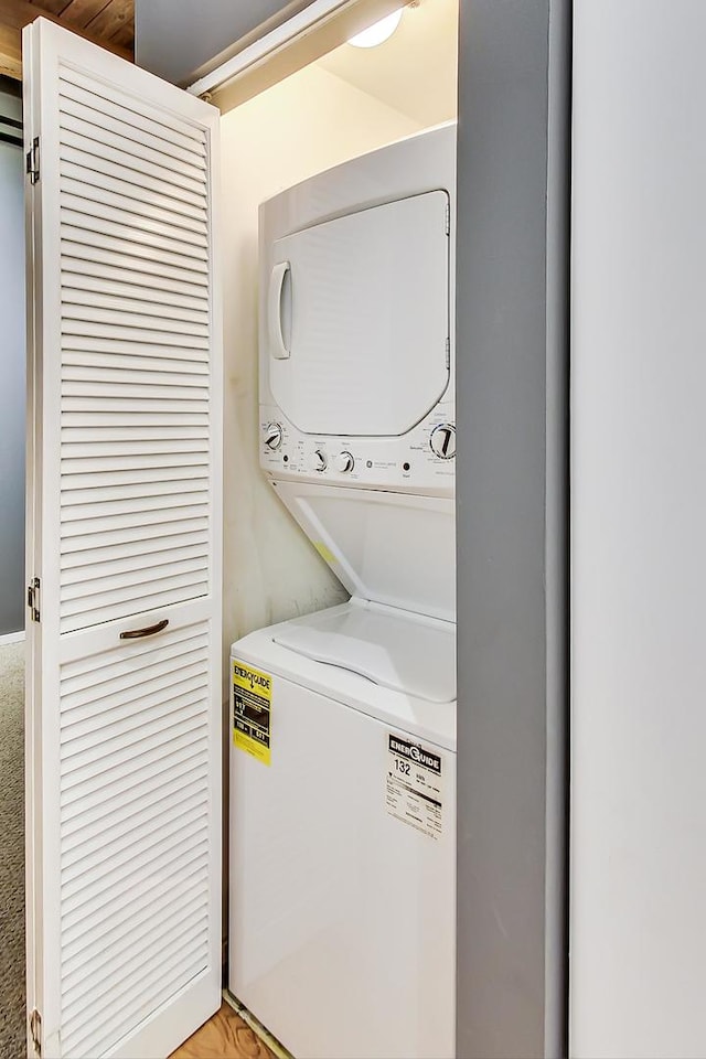 clothes washing area featuring stacked washer and clothes dryer and laundry area