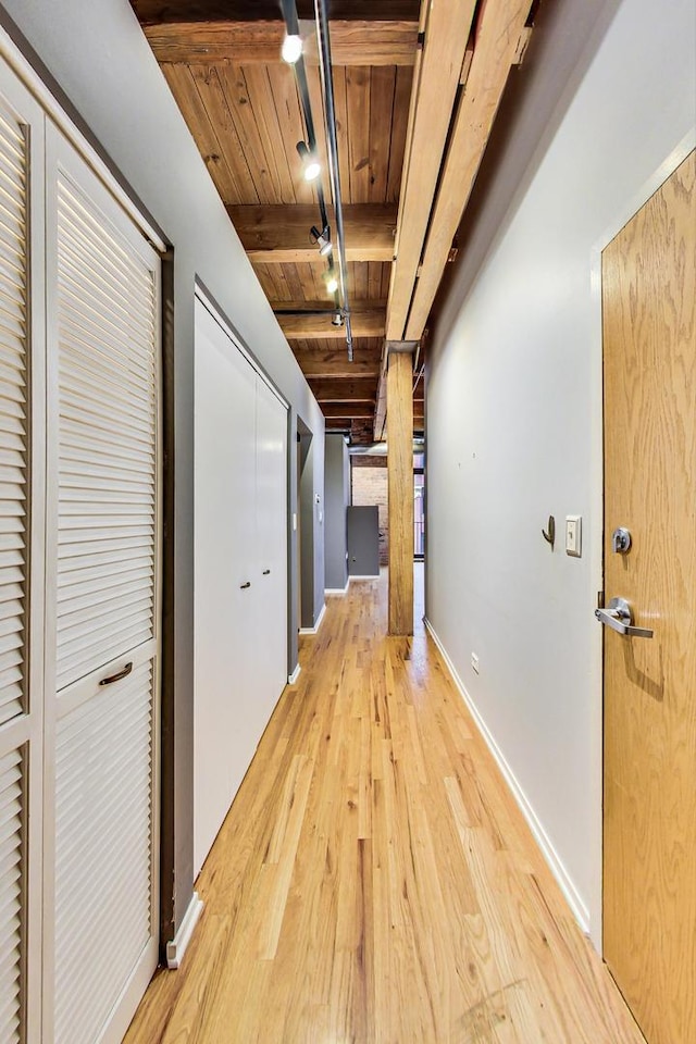 hall featuring wooden ceiling, baseboards, light wood-type flooring, beamed ceiling, and rail lighting