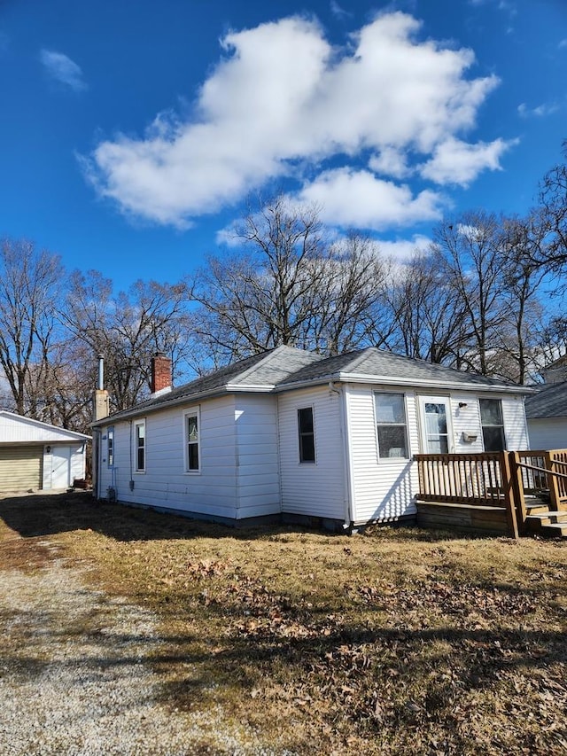 rear view of house featuring a chimney, a wooden deck, and an outdoor structure