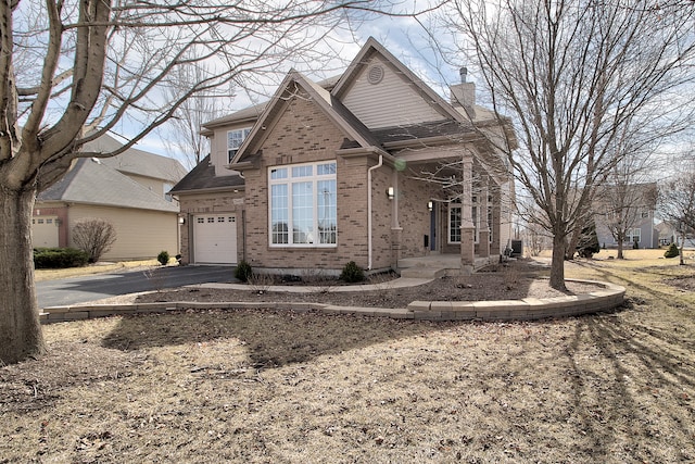 view of front of house with a garage, brick siding, driveway, and a chimney