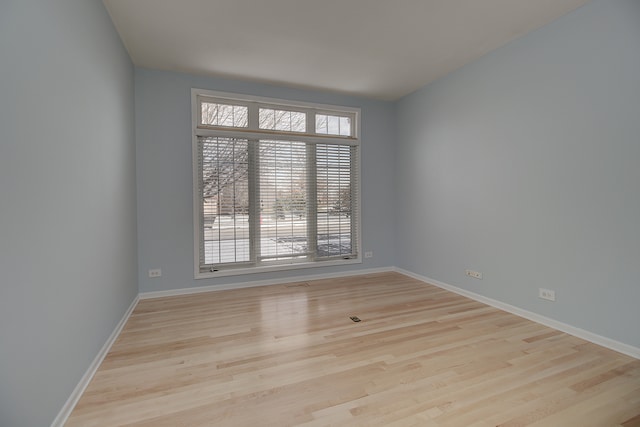 unfurnished room featuring visible vents, baseboards, and wood finished floors