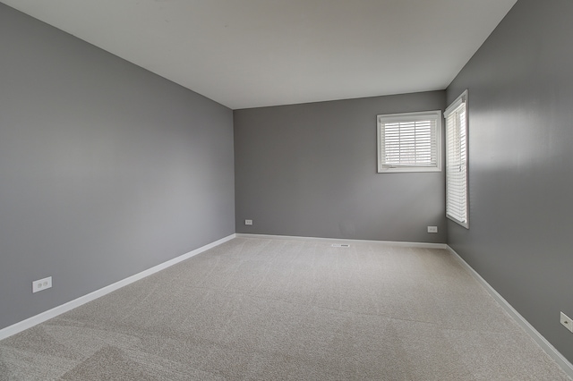 unfurnished room featuring light carpet and baseboards