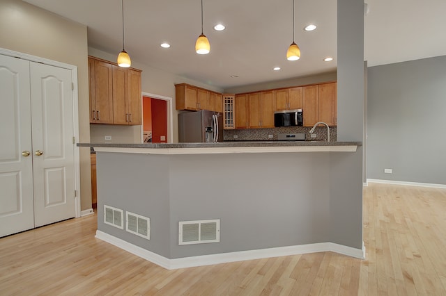 kitchen featuring light wood-type flooring, visible vents, appliances with stainless steel finishes, and brown cabinetry