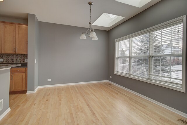 26403 W Red Apple Rd, Plainfield, IL 60585 - unfurnished dining area featuring a skylight, light wood-type flooring, a chandelier, and baseboards