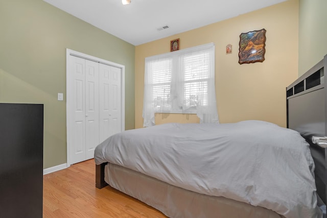 bedroom featuring visible vents, a closet, light wood-style flooring, and baseboards