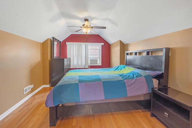 bedroom featuring cooling unit, visible vents, baseboards, vaulted ceiling, and light wood-type flooring