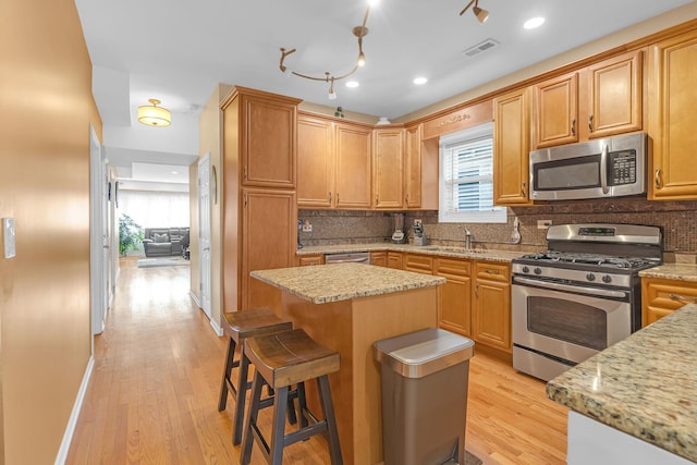 kitchen featuring a sink, visible vents, light wood-style floors, appliances with stainless steel finishes, and tasteful backsplash