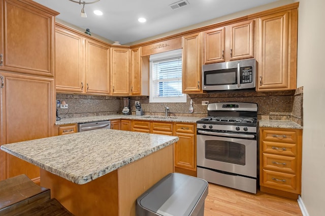 kitchen featuring visible vents, decorative backsplash, stainless steel appliances, and a sink