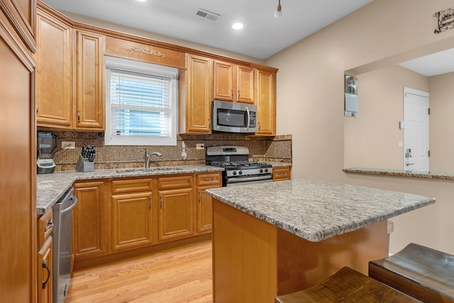 kitchen featuring a sink, visible vents, appliances with stainless steel finishes, decorative backsplash, and a kitchen bar