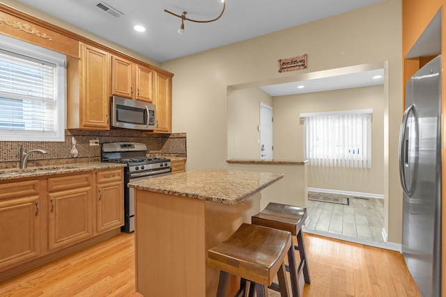 kitchen featuring stainless steel appliances, visible vents, a sink, and light wood finished floors