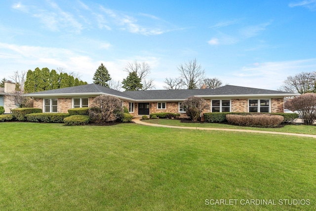 single story home featuring brick siding, a chimney, and a front yard