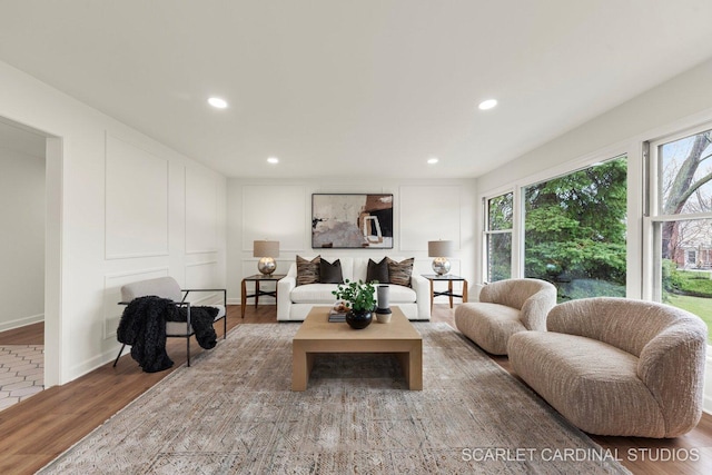 living area featuring recessed lighting, wood finished floors, and a decorative wall