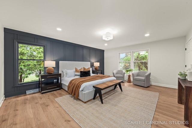 bedroom with recessed lighting, baseboards, light wood finished floors, visible vents, and a decorative wall