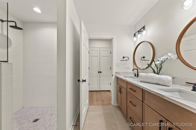 full bath featuring double vanity, a walk in shower, a sink, and tile patterned floors