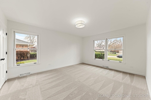 unfurnished room with visible vents, a healthy amount of sunlight, and light carpet