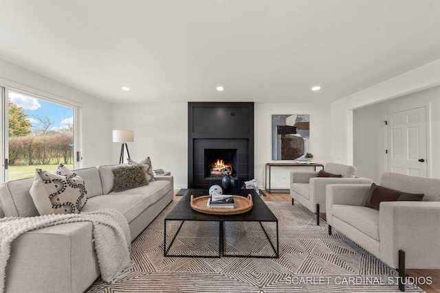 living room with baseboards, recessed lighting, light wood-style flooring, and a large fireplace