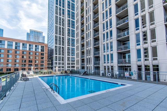 view of pool featuring a city view and fence