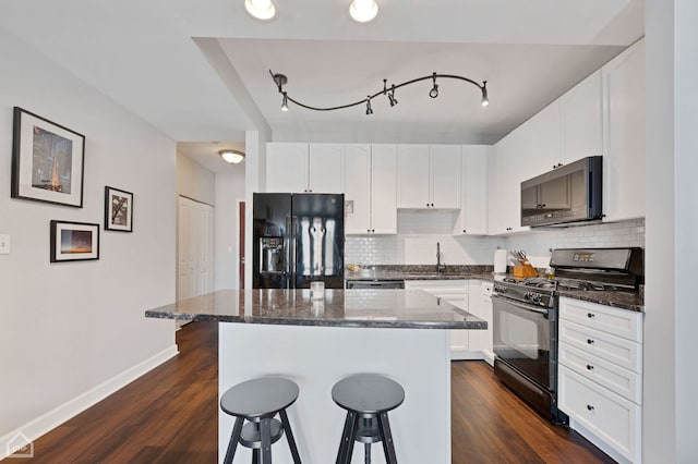 kitchen with tasteful backsplash, a breakfast bar, and black appliances