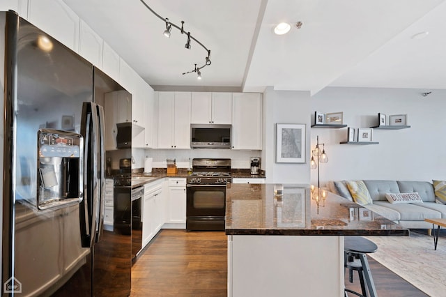 kitchen featuring dark wood finished floors, a kitchen island, a breakfast bar area, open floor plan, and black appliances