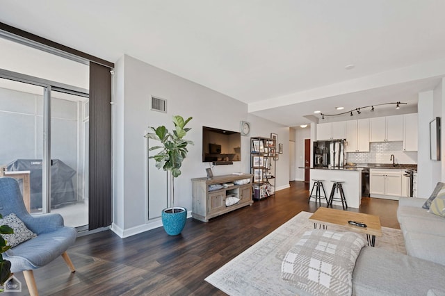 living room with dark wood-style flooring, visible vents, and baseboards