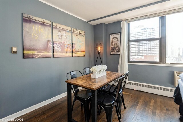 dining space featuring a baseboard radiator, wood finished floors, and baseboards