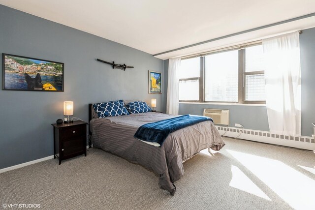 carpeted bedroom with a baseboard heating unit, a wall mounted air conditioner, and baseboards