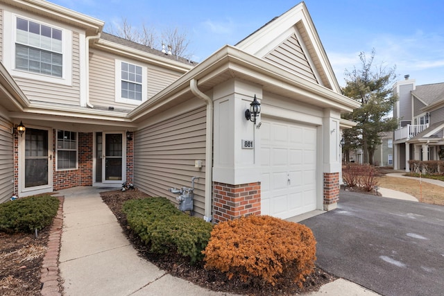 exterior space featuring an attached garage, driveway, and brick siding