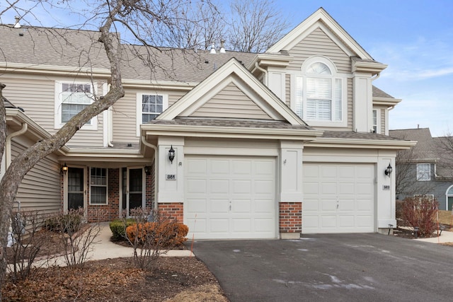 view of front of home with roof with shingles, aphalt driveway, and brick siding