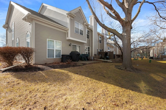 back of property with a chimney and a lawn