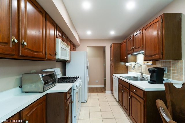 kitchen featuring white appliances, decorative backsplash, light countertops, and a sink