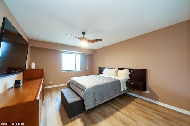 bedroom with light wood finished floors, a ceiling fan, and baseboards