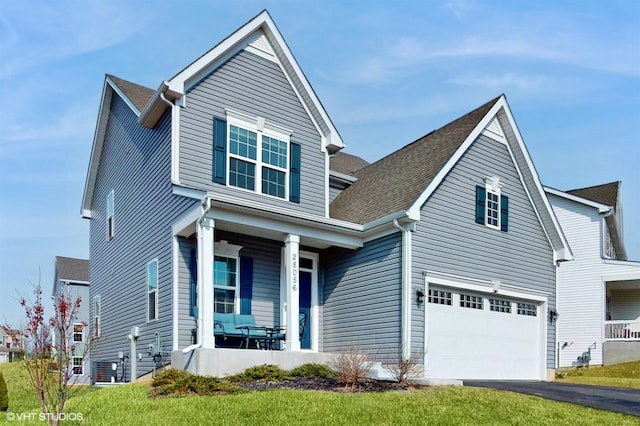 traditional-style house with a garage, covered porch, and aphalt driveway