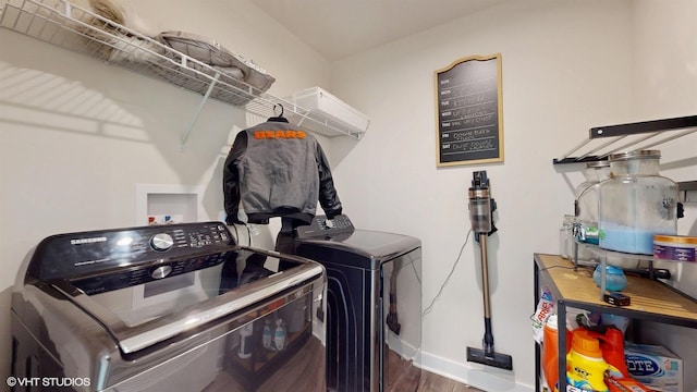 laundry area with laundry area, washing machine and dryer, baseboards, and wood finished floors