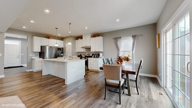 kitchen with light wood finished floors, appliances with stainless steel finishes, a sink, and visible vents