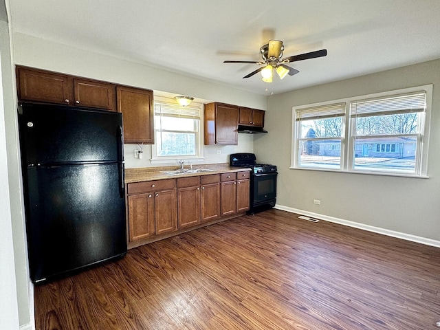 kitchen featuring baseboards, dark wood-type flooring, under cabinet range hood, black appliances, and a sink