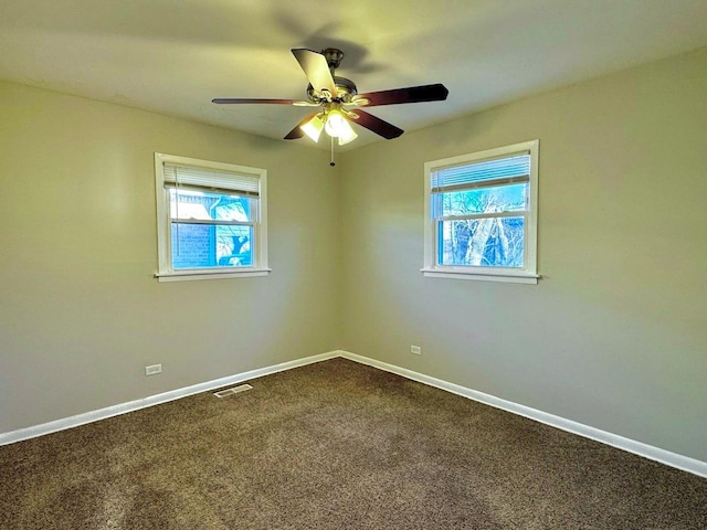 spare room featuring ceiling fan, baseboards, visible vents, and dark carpet