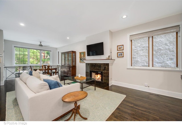 living area with recessed lighting, dark wood-type flooring, visible vents, baseboards, and a tiled fireplace